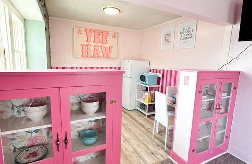 Russell Apartment | Rhinestone Cowgirl is a chic pink-inspired upper-level apartment just blocks from downtown Russell. Enjoy a cozy bedroom, living area with Smart TV, kitchenette, full bath, private balcony, and shared backyard with grill, firepit, and laundry.