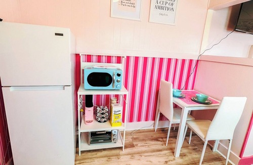 Russell Apartment | Rhinestone Cowgirl is a chic pink-inspired upper-level apartment just blocks from downtown Russell. Enjoy a cozy bedroom, living area with Smart TV, kitchenette, full bath, private balcony, and shared backyard with grill, firepit, and laundry.